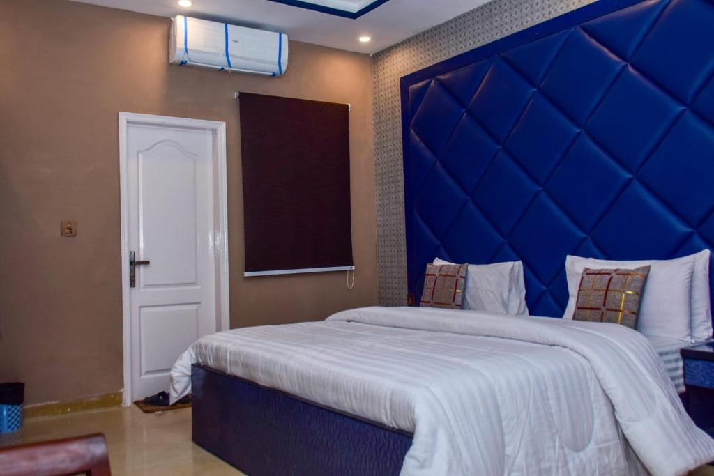 卡拉奇Clifton Rezidor的一间卧室配有一张大床和蓝色床头板