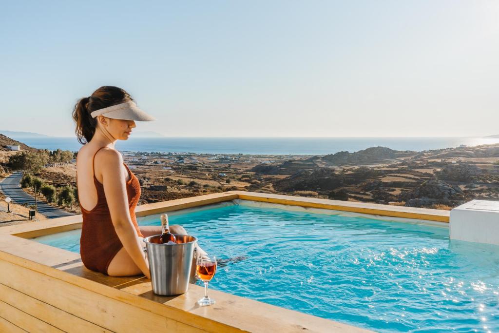 纳克索斯岛卡斯特拉基Naxos Aethereal View的坐在游泳池旁的女人,喝一杯葡萄酒