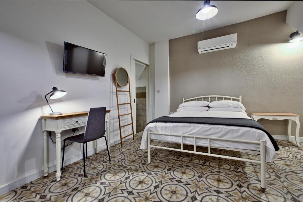瓦莱塔Chateau La Vallette - Barrakka Suite的一间卧室配有一张床、一张书桌和一台电视