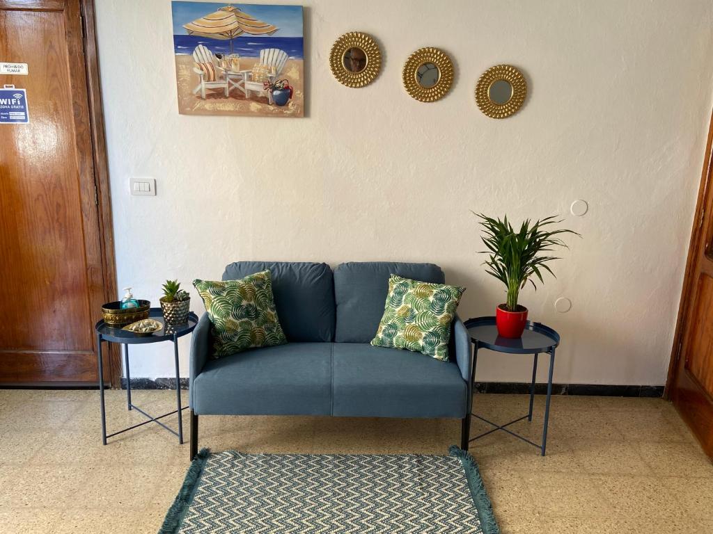 Playa del BurreroSarahs Kite Vivienda Vacacional en Playa del Burrero的客厅设有一张蓝色的沙发,配有两张桌子