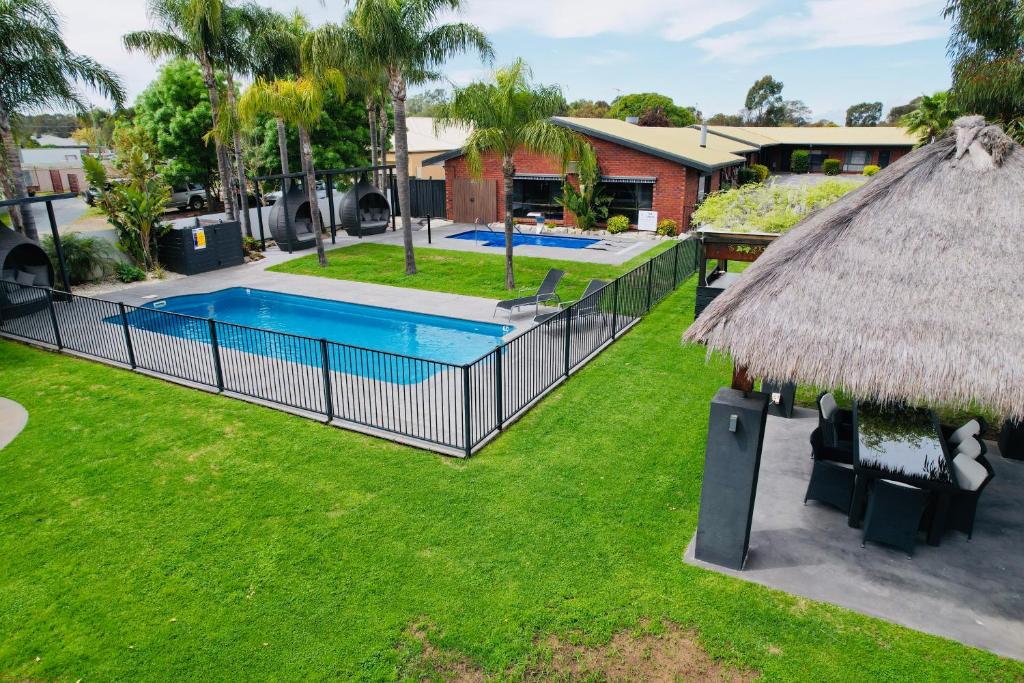 科罗瓦Federation Motel Resort - Corowa的后院设有游泳池和茅草屋顶