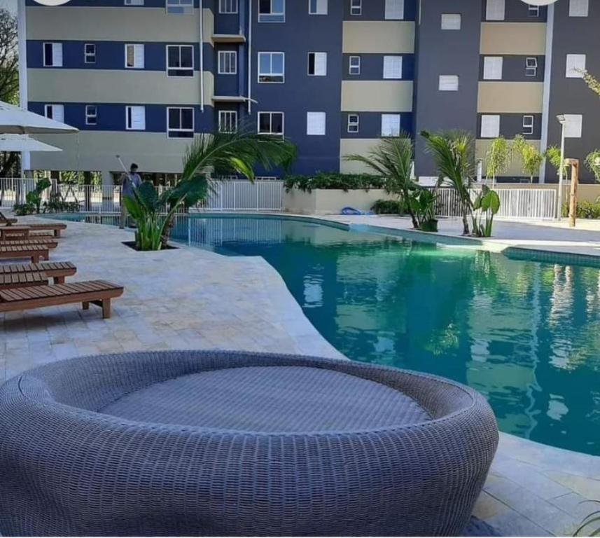 乌巴图巴Paradaise Resort Ubatuba的一座游泳池,旁边是一座建筑,配有藤椅