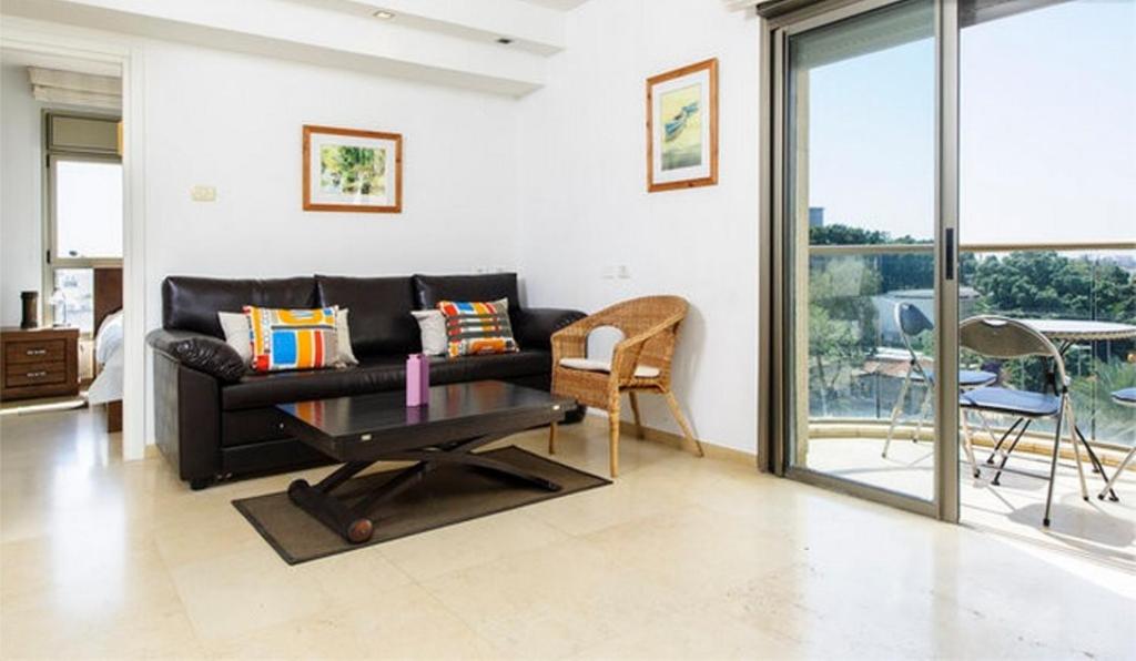 赖阿南纳Holiday Raanana Apartments的客厅配有黑色沙发和桌子