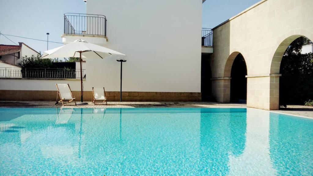 圣玛丽亚巴格诺Blue Paradise的一个带两把椅子和遮阳伞的游泳池