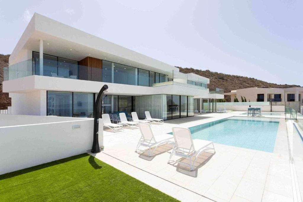 阿德耶New Home Costa Adeje Luxurious Private Villa的一座带游泳池和椅子的大房子