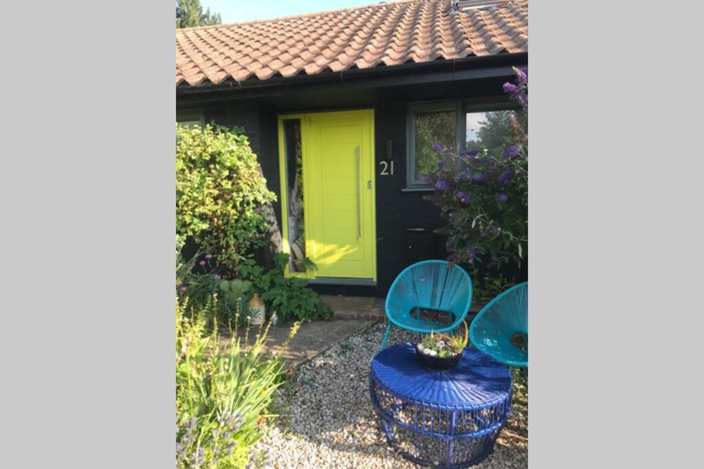 惠茨特布尔The Yellow Door Whitstable - Peaceful retreat close to beach的花园设有2把蓝色椅子和黄色门
