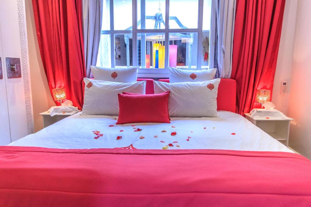 马拉喀什里亚德古斯塔旅馆的一张带红色和白色枕头的床和窗户