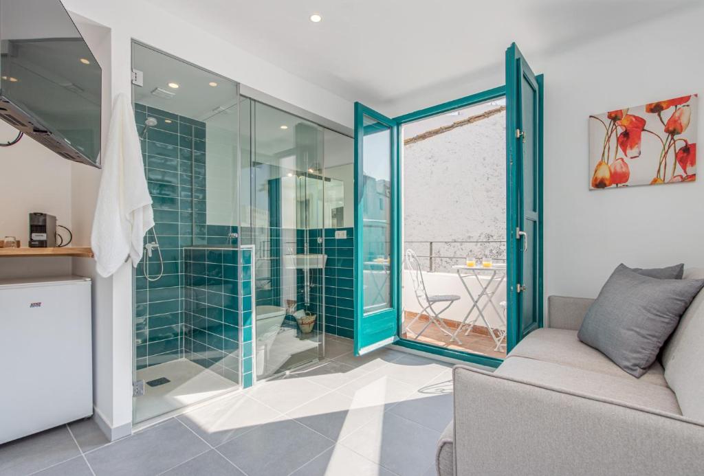 卡达克斯Habitacions Bellaire Cadaqués的一间带玻璃淋浴和沙发的浴室