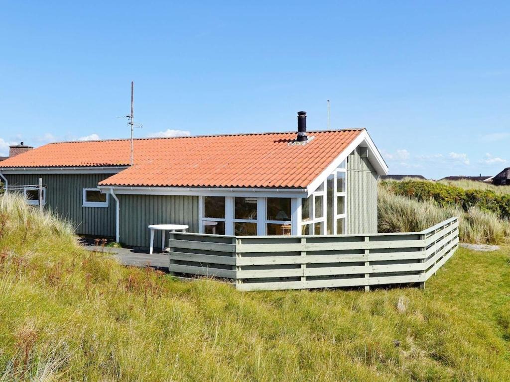 凡岛6 person holiday home in Fan的海滩上一座带橙色屋顶的小房子