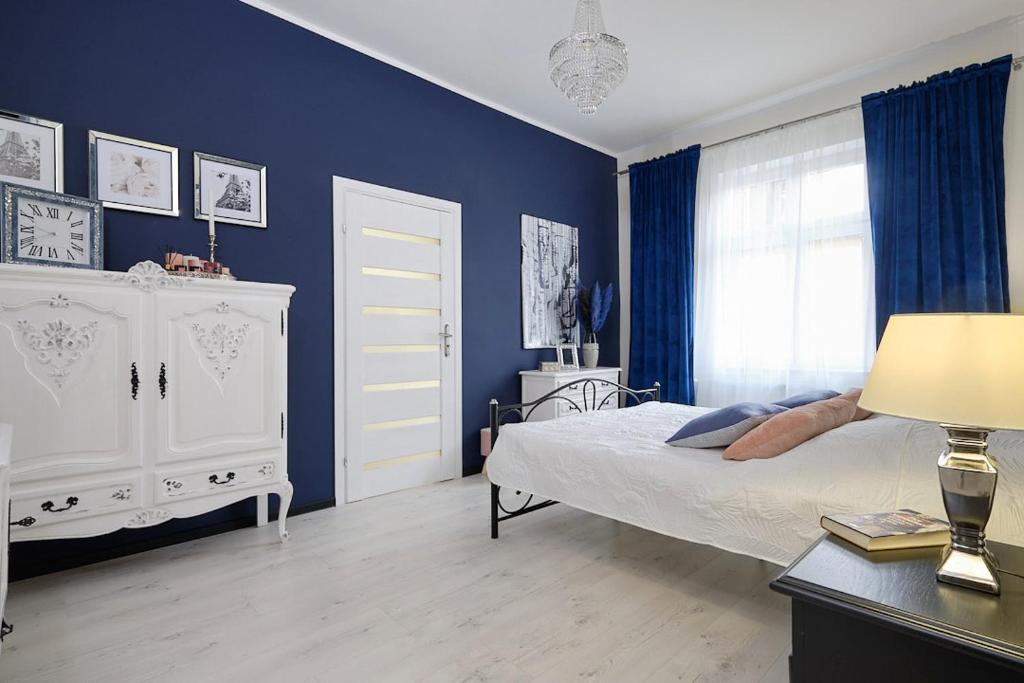 斯扎瓦诺泽德霍Art Apartment Szczawno Zdrój的一间卧室设有一张床和蓝色的墙壁