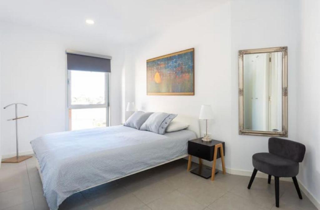厄尔梅达诺Modern seafront flat with a private garage的白色卧室配有床和椅子