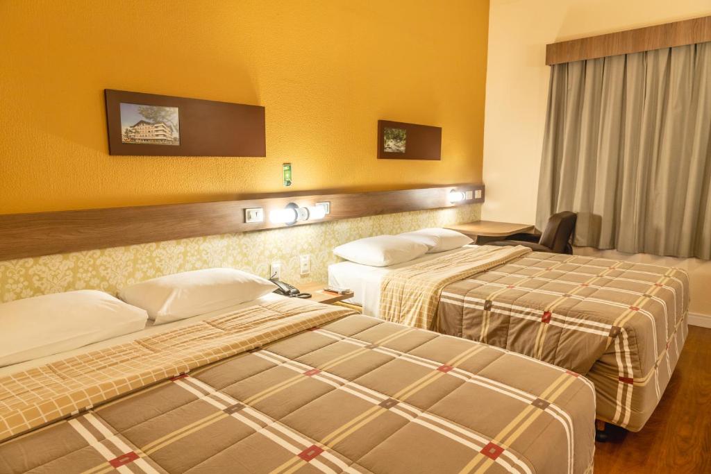 布卢梅瑙布卢梅诺10号酒店的两张床位于带黄色墙壁的酒店客房
