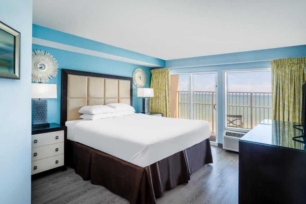 默特尔比奇Palette Resort Myrtle Beach by OYO的一间带大床和阳台的大卧室