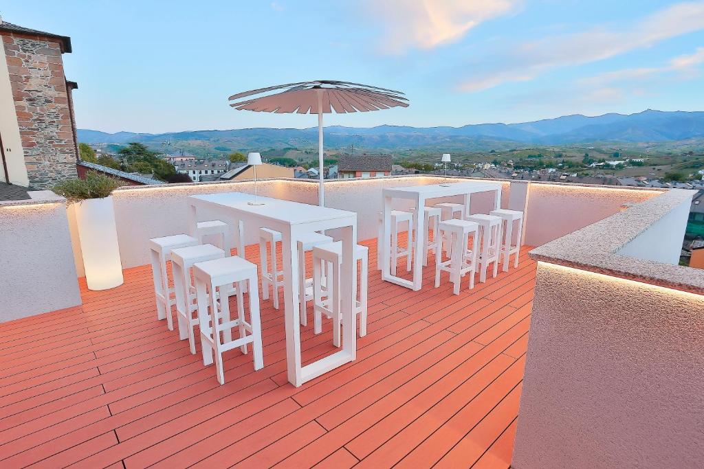 蓬费拉达Azotea Suites的阳台上的一排桌椅,配有雨伞