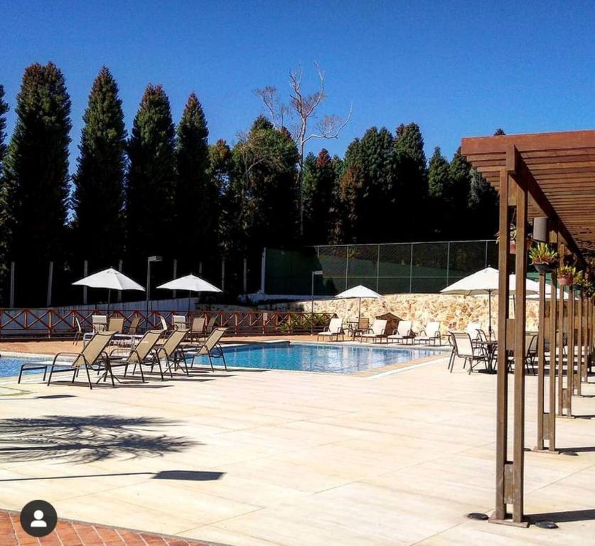 佩德拉阿祖尔Condomínio Vista Azul hotel的游泳池旁配有椅子和遮阳伞