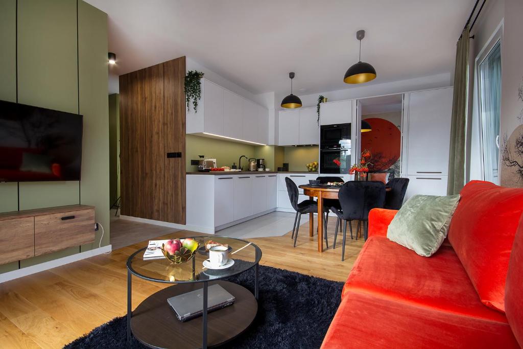 科沙林W&K Apartments - Balance Suite的一间带红色沙发的客厅和一间厨房