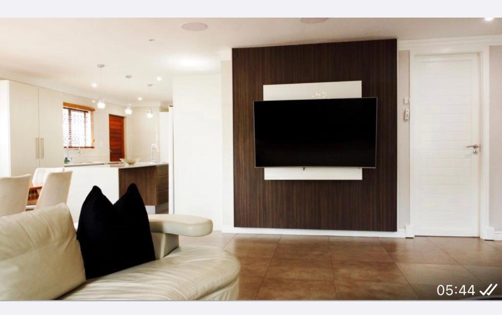 阿曼济姆托蒂Precious Paradise Villa的客厅配有沙发和墙上的电视