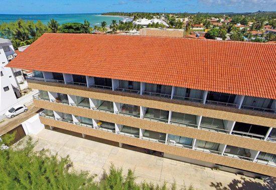 塔曼达雷Praia dos Carneiros Flat Hotel Apto Completo的一座公寓楼,拥有橙色的屋顶和海洋