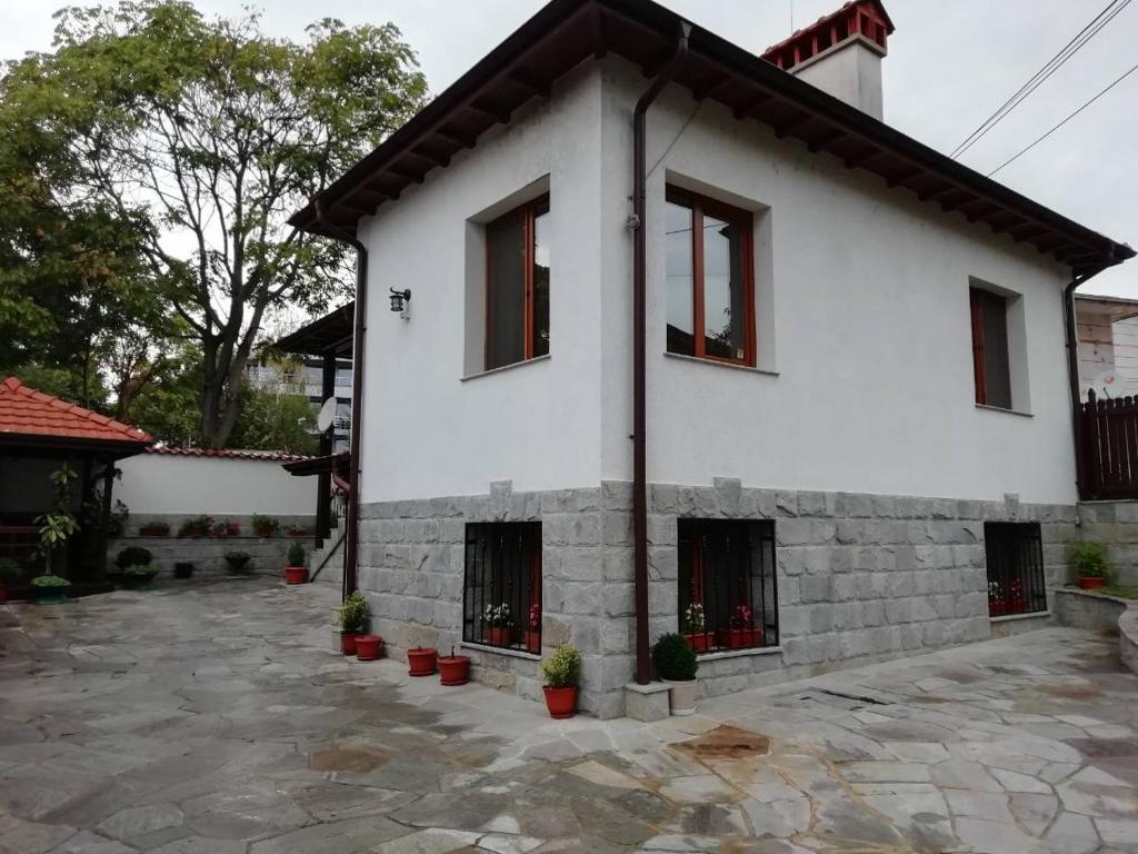 斯特雷尔恰Къща в центъра на Стрелча, джакузи с минерална вода的白色的房子,有窗户和盆栽植物