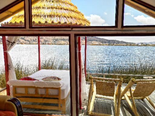 普诺Uros Qhota Uta Lodge的窗户享有水景,配有一张床和椅子