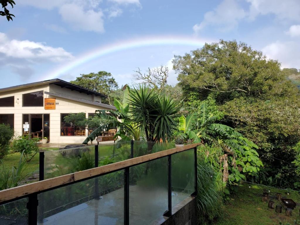 蒙泰韦尔德哥斯达黎加OutBox Inn的天上方的彩虹,在一座带池塘的房子上方