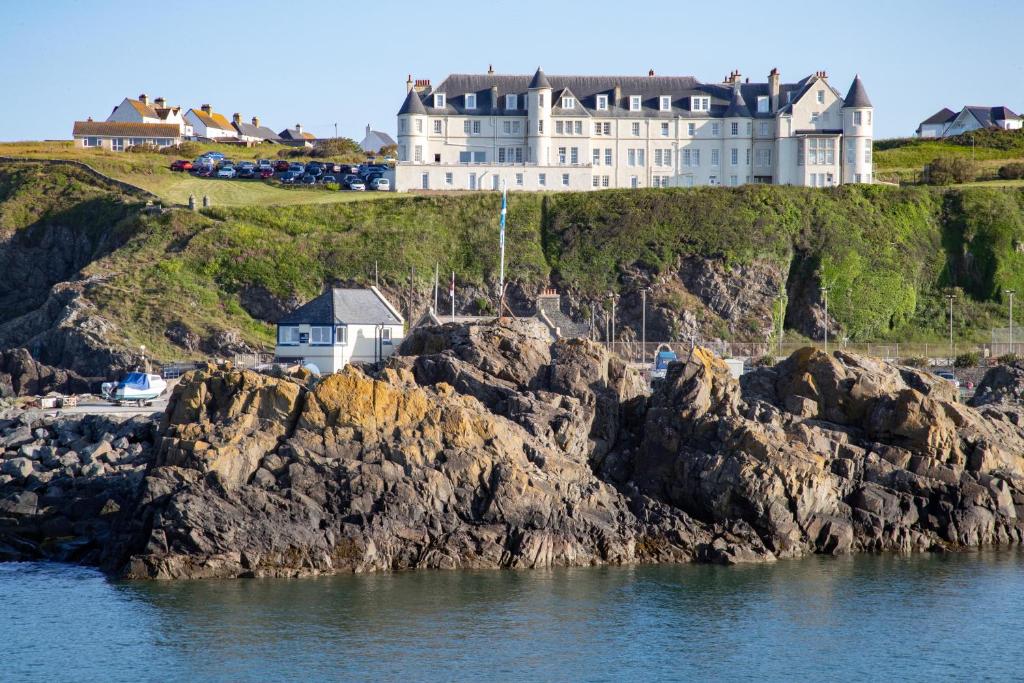 波特帕特里克The Portpatrick Hotel by Compass Hospitality的悬崖顶部的城堡,靠近水面