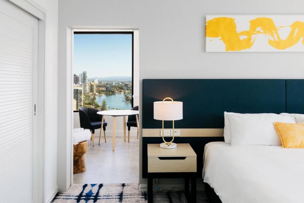 黄金海岸voco Gold Coast, an IHG Hotel的一间卧室配有一张床和一张带台灯的桌子