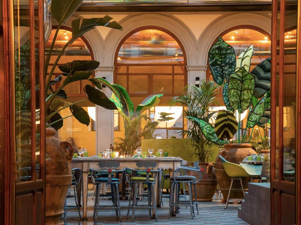 佛罗伦萨25hours Hotel Florence Piazza San Paolino的一间设有桌椅的餐厅,种植了植物