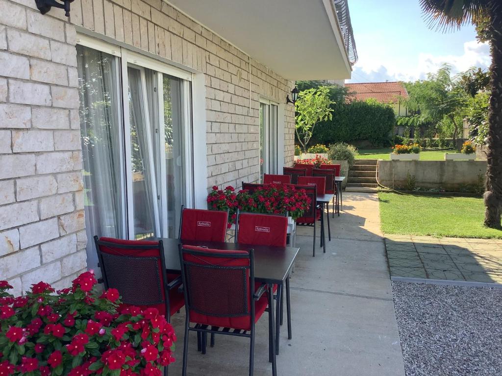 Široki BrijegSobe Pipić的一排桌子,有红色的椅子和鲜花