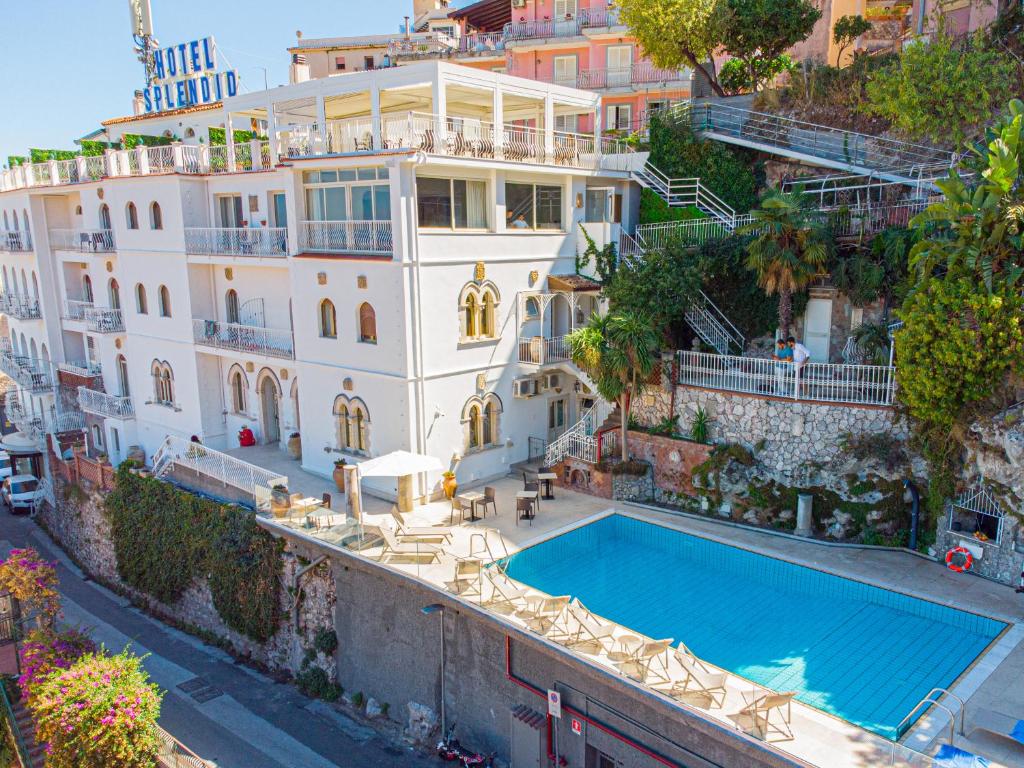 陶尔米纳Splendid Hotel Taormina的一座白色的大建筑,前面设有一个游泳池