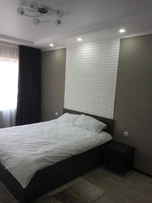 奇姆肯特Квартира的卧室配有白色的砖墙床