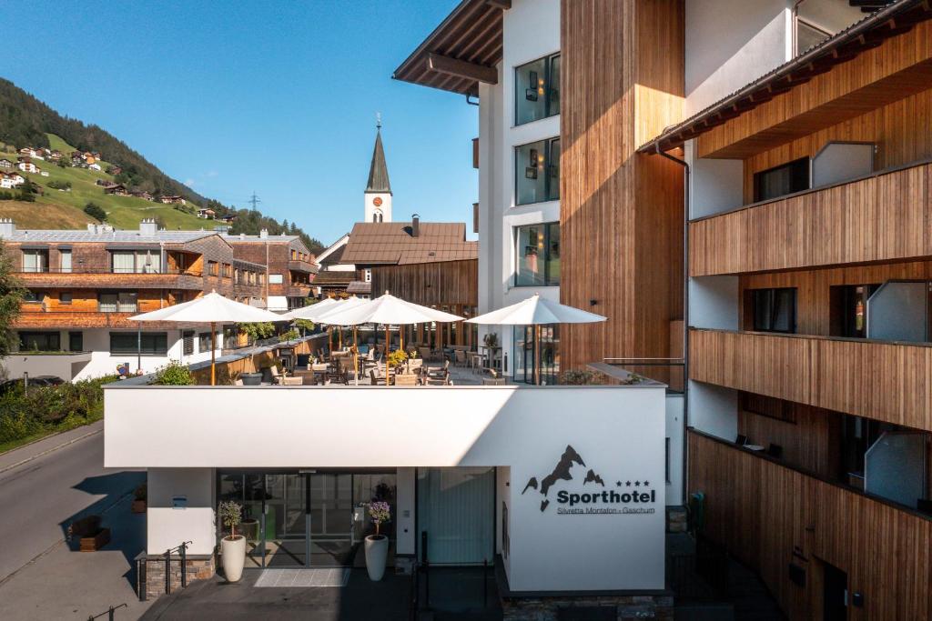 加舒恩斯维里塔蒙塔峰体育酒店的享有带桌子和遮阳伞的建筑的外部景色
