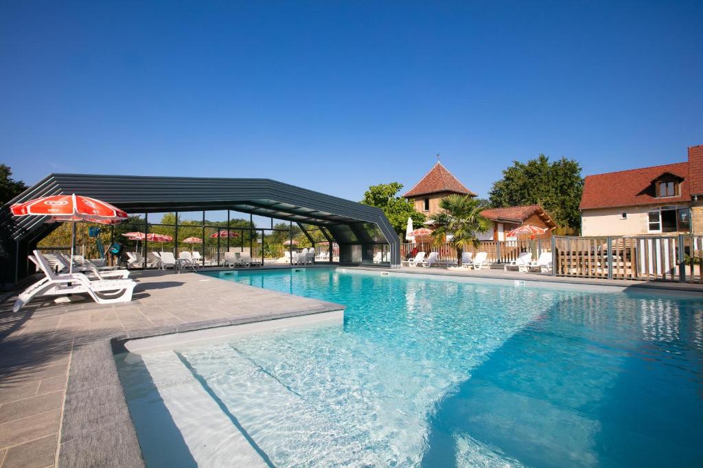 罗卡马杜尔帕迪玛朵野营酒店的一个带遮阳伞和椅子的游泳池