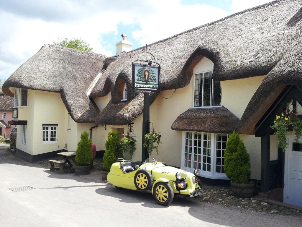 WinsfordThe Royal Oak Exmoor的停在茅草屋前的绿色汽车