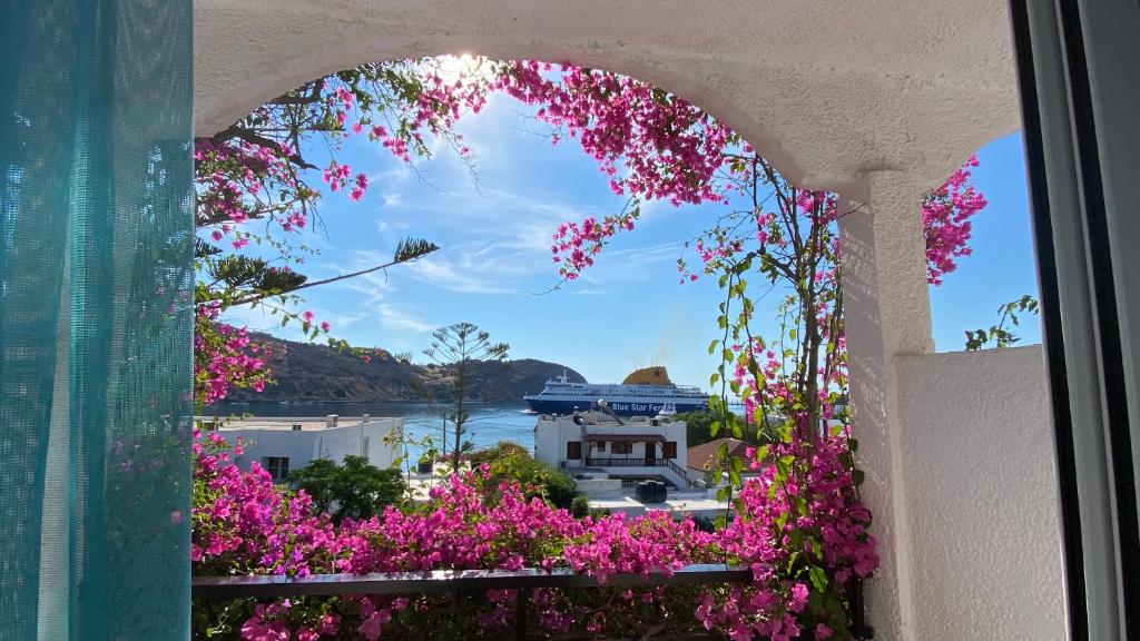 斯科拉斯卡拉酒店的窗户,有粉红色的花朵,享有海港的景色