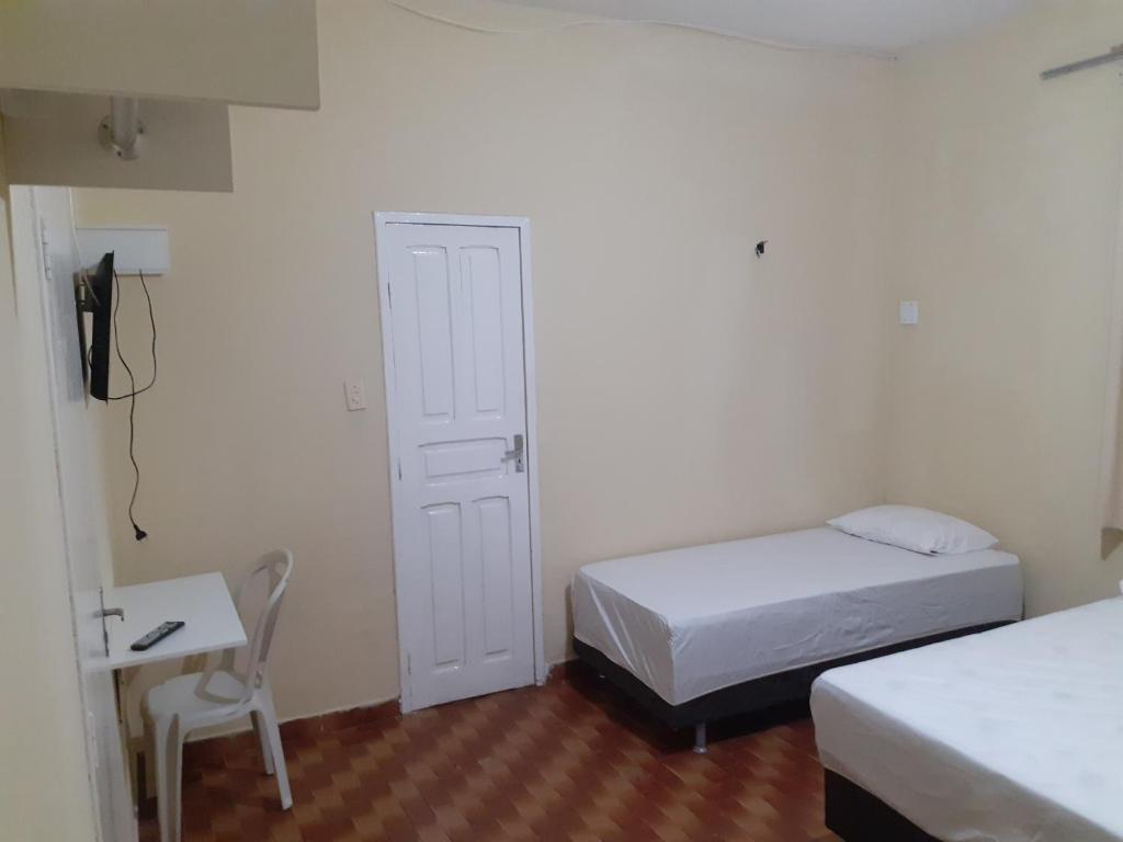 福塔莱萨Hostel Parquelândia的一间卧室配有两张床、一张桌子和一把椅子