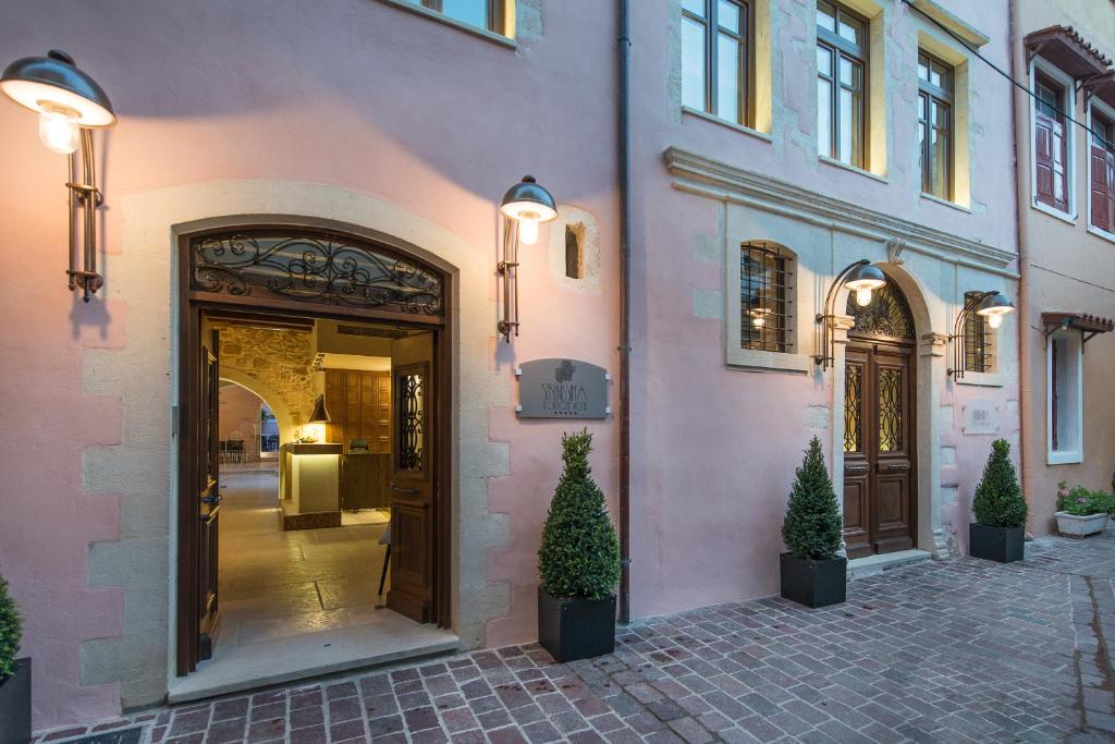 干尼亚瑟乐尼斯玛精品酒店的粉红色的建筑,有门和两棵盆栽树木