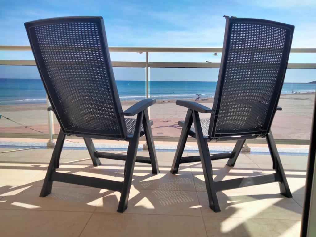 拉皮内达PINEDA BEACH 1a línea de mar & parking的两把椅子坐在俯瞰海滩的阳台上