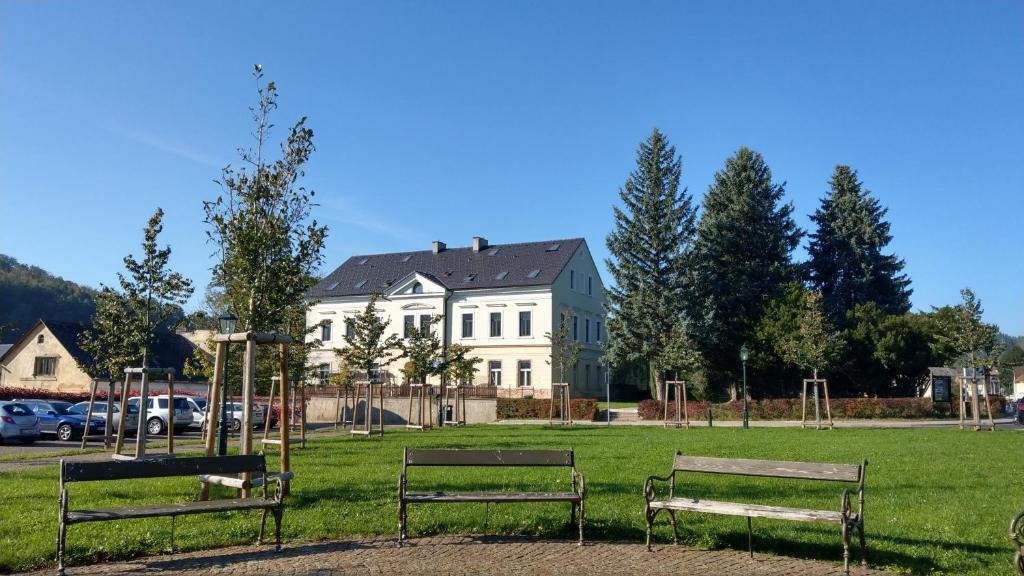 海尼采Apartmány Klášterní 84的两把长椅在房子前面的公园里