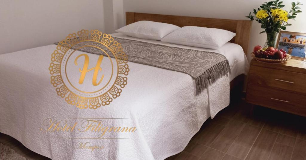 蒙波斯Hotel Filigrana Mompox的一张带白色毯子和金色徽章的床