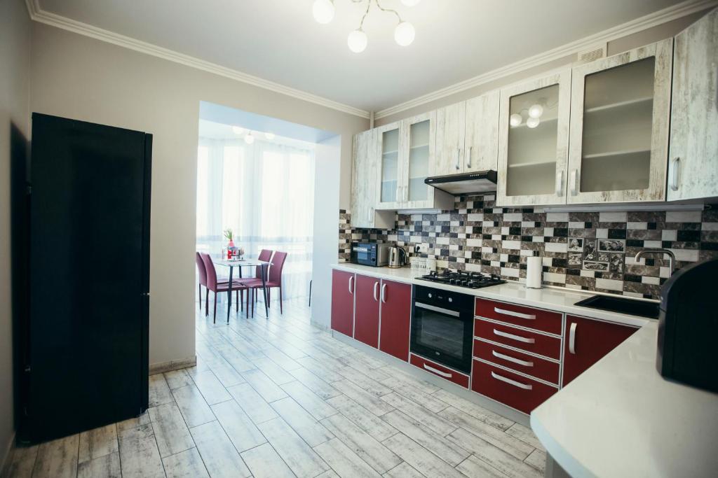 切尔诺夫策Atlant apartments的厨房配有红色橱柜和桌椅