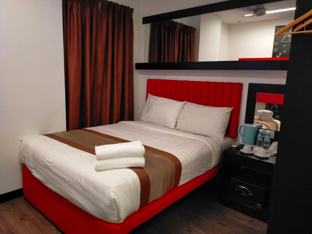 吉隆坡Lazdana Hotel Kuala Lumpur的一间卧室配有一张大床和红色床头板