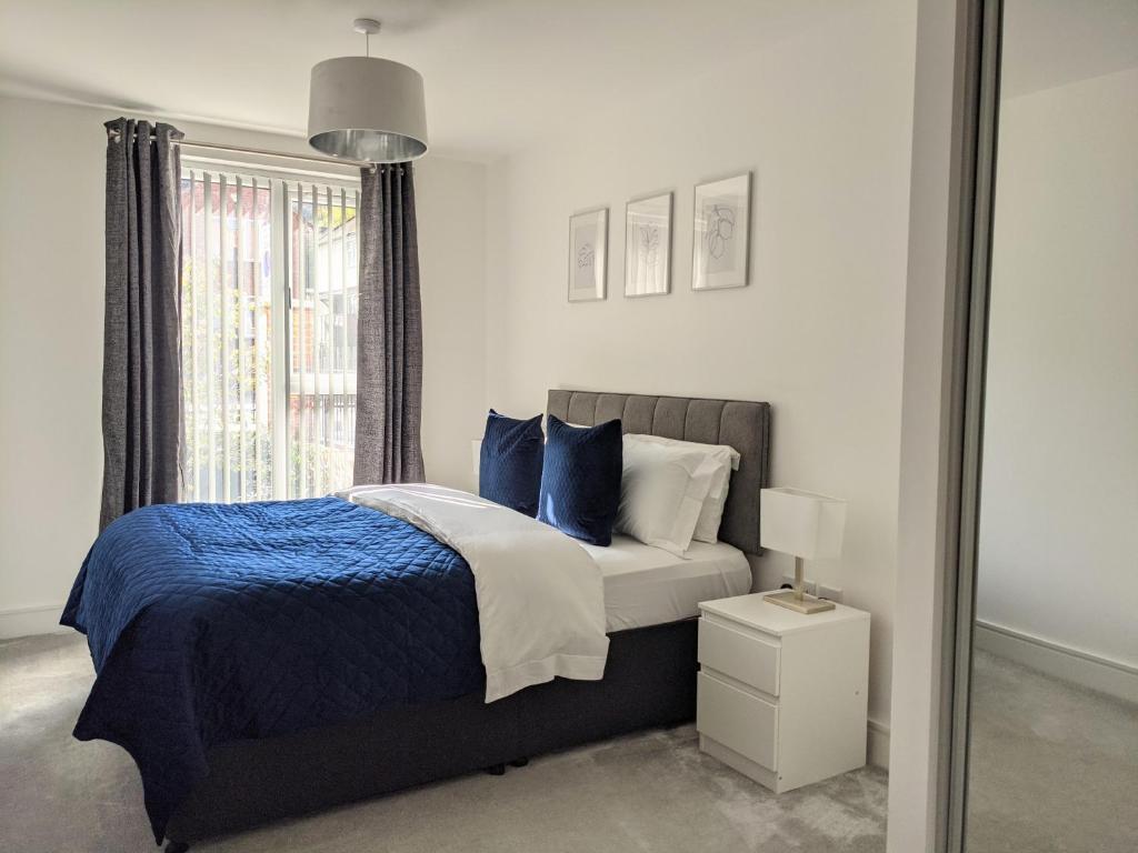 海维康Suffield Lodge by Wycombe Apartments的一间卧室配有一张带蓝色枕头的床和一扇窗户。