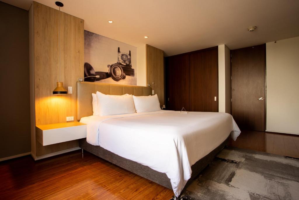 马尼萨莱斯Quo Quality Hotel的卧室配有一张白色大床和木制橱柜。