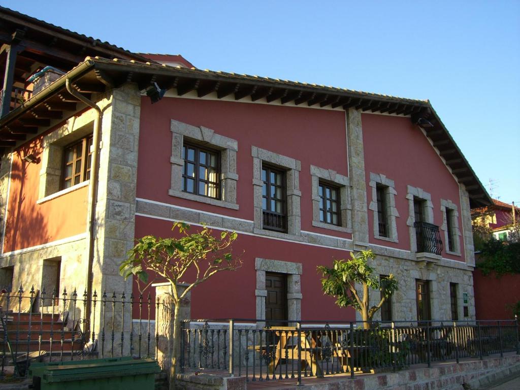 里瓦德塞利亚Hotel Rural La Curva Ribadesella的前面有树木的红色建筑