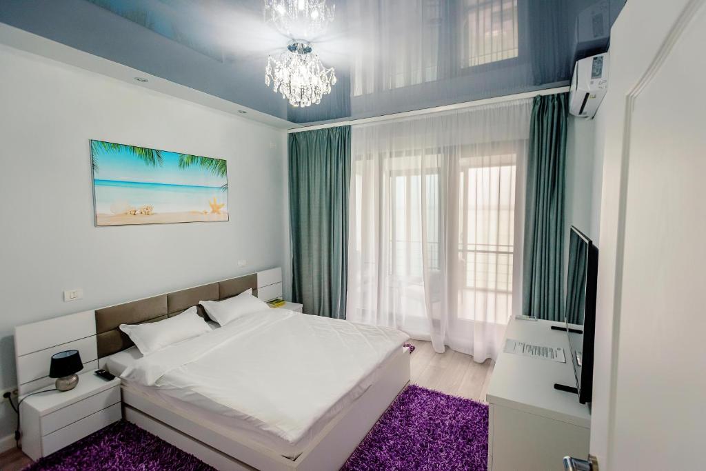 马马亚Lamera Residence Mamaia Apartments的卧室配有白色的床和紫色地毯。