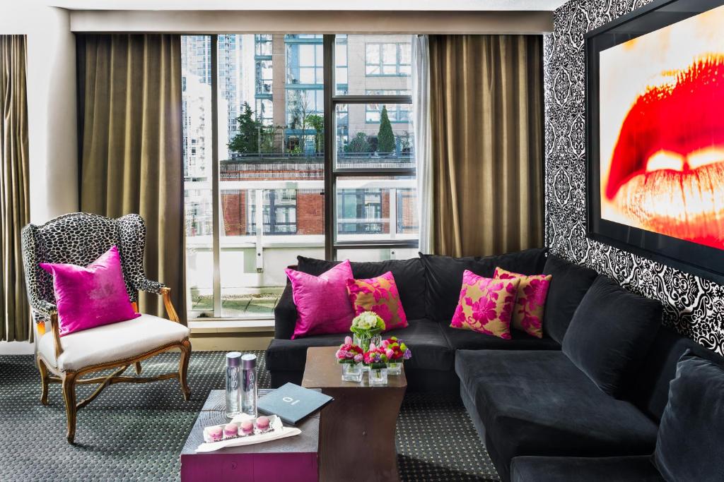温哥华OPUS Vancouver的客厅配有黑色沙发和粉红色枕头。