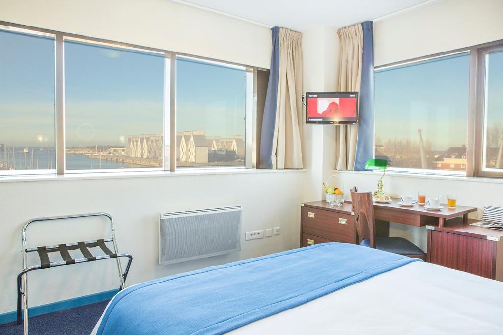 敦刻尔克敦刻尔克莱斯根斯德梅尔波普平斯酒店的卧室配有一张床、一张书桌和窗户。