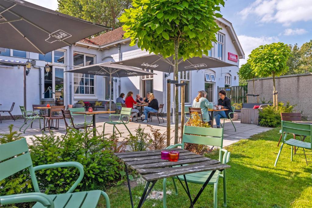 哈莱姆Stayokay Hostel Haarlem的一个带桌椅和遮阳伞的庭院