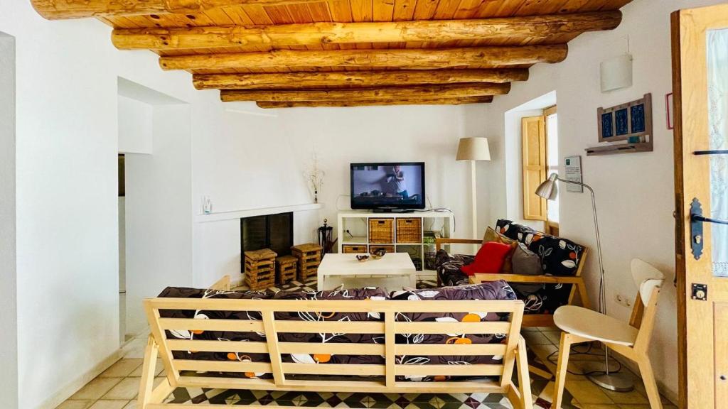 利纳雷斯德拉谢拉La Cantarera的客厅拥有白色的墙壁和木制天花板。